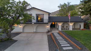 View of front facade with an attached garage, concrete driveway, a balcony, a front lawn, and brick siding