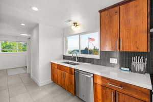 Kitchen featuring wood finish cabinets, dishwasher, recessed lighting, a textured ceiling, and decorative backsplash