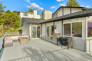 Back of property featuring stucco siding, a sunroom, a shingled roof, and outdoor lounge area