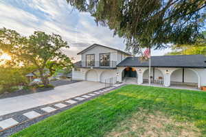 View of front of house featuring an attached garage, concrete driveway, a lawn, a balcony, and a shingled roof