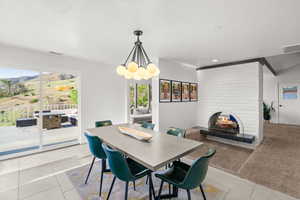 Dining room featuring a fireplace, light tile patterned floors, and a chandelier