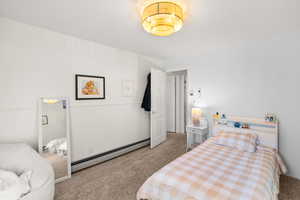 Bedroom featuring light carpet and baseboard heating