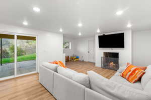 Living room with light wood-style floors, a tile fireplace, and recessed lighting