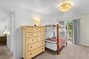 Carpeted bedroom with a textured ceiling and access to outside