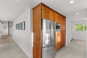 Kitchen featuring stainless steel appliances, wood finish cabinetry, recessed lighting, and light countertops