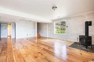 Unfurnished living room with a wood stove, light wood-style flooring, and wooden walls
