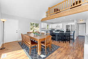 Open-concept living area featuring wood-finish flooring, vaulted ceilings, and a wood-beam loft railing
