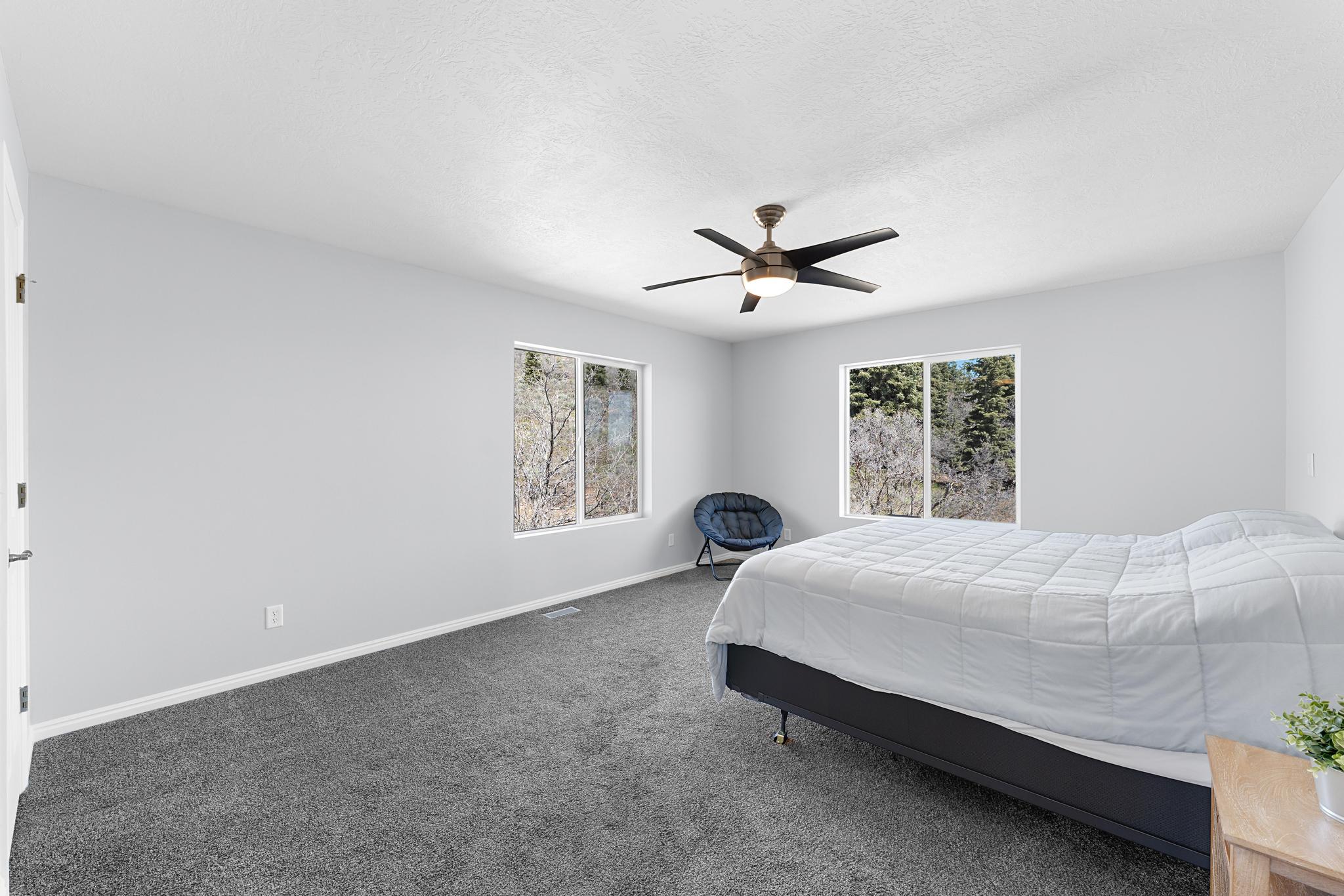 Spacious room featuring gray wall paint, gray carpeting, and multiple windows