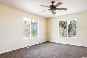 Unfurnished room with dark colored carpet, a ceiling fan, and a textured ceiling