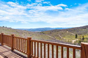 Expansive outdoor deck with natural wood railing overlooking a distant mountain range and verdant valleys