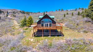 Wood-sided chalet-style residence featuring a prominent A-frame window design, a full-width upper deck with wood railing, and a lower level patio