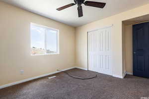 Unfurnished bedroom featuring carpet flooring, a ceiling fan, a closet, and a textured ceiling