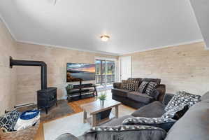 Living area featuring a cast iron wood-burning stove on a stone tile hearth, wood-finish flooring, plank wall finishes, and a sliding glass door opening to a balcony with mountain scenery