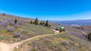 Hillside residence with a green roof, multiple outdoor decks, and a detached garage, set against a mountainous backdrop