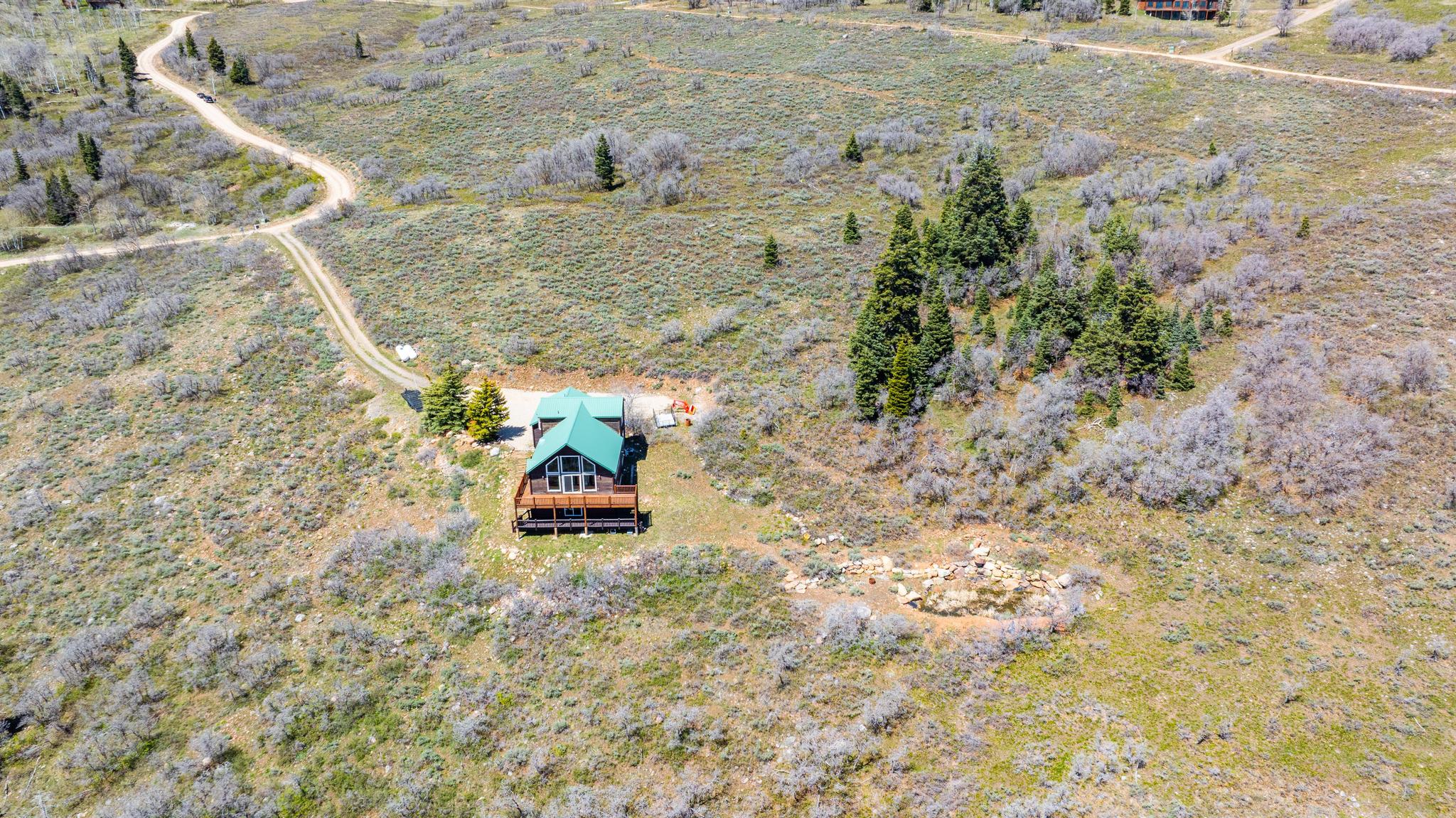 Wood-sided A-frame cabin featuring a green metal roof and a full-width wood deck