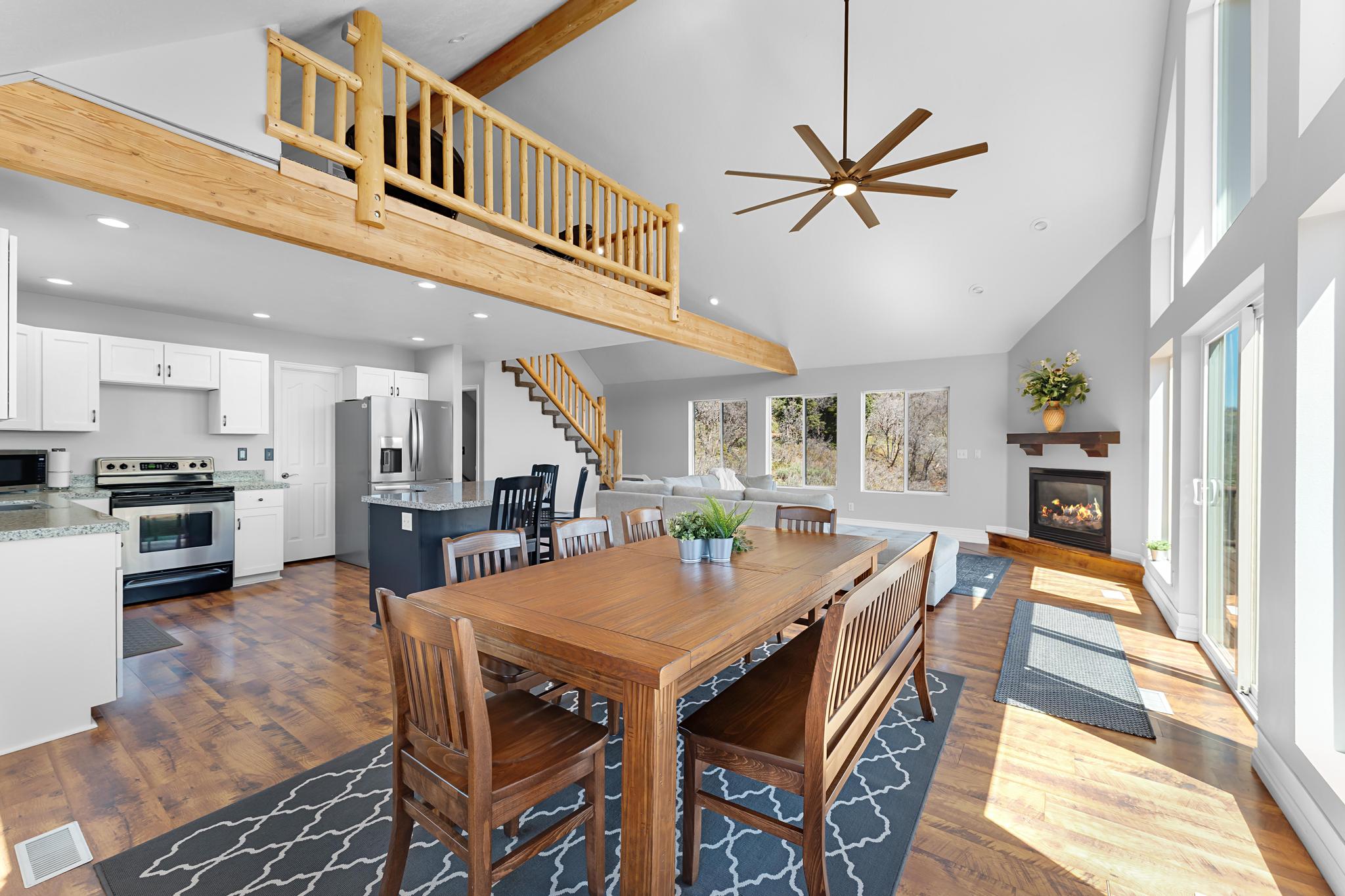 Vaulted great room featuring wood-finish flooring, a contemporary ceiling fan, and abundant natural light from multiple windows