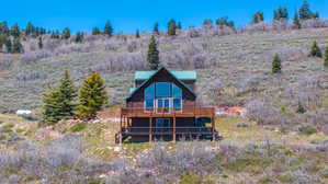 Log cabin exterior featuring a steep-pitched metal roof, an expansive deck, and a wall of windows