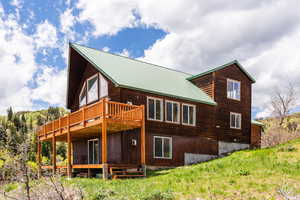 Rear view of property featuring a wooden deck and a metal roof