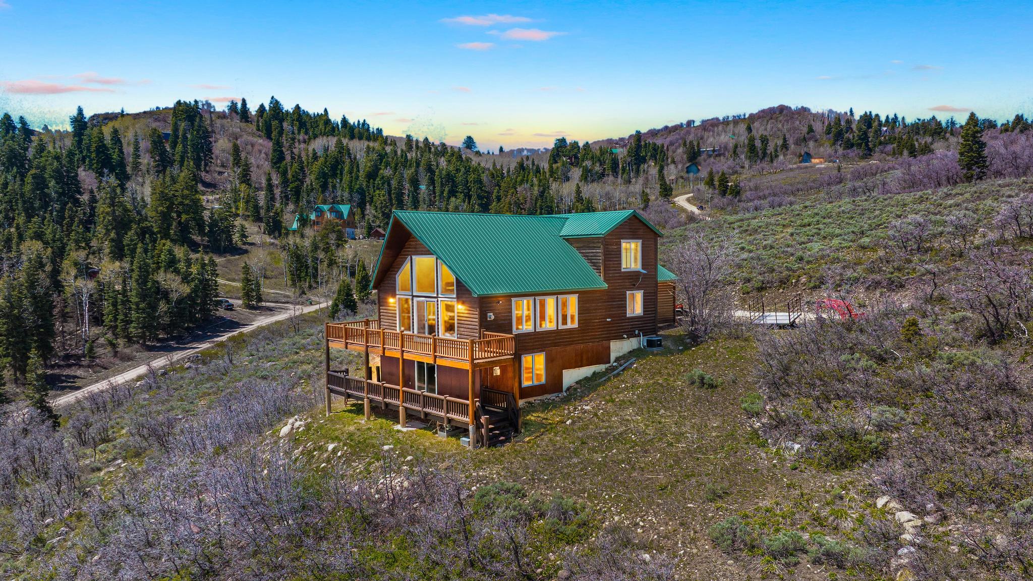 Wood-sided mountain home featuring a green metal roof and a multi-level deck