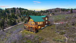 Wood-sided mountain home featuring a green metal roof and a multi-level deck