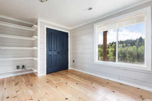 Foyer entrance with light wood-style floors and wood walls