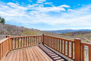Expansive wood deck with log-style railings overlooking a mountainous landscape