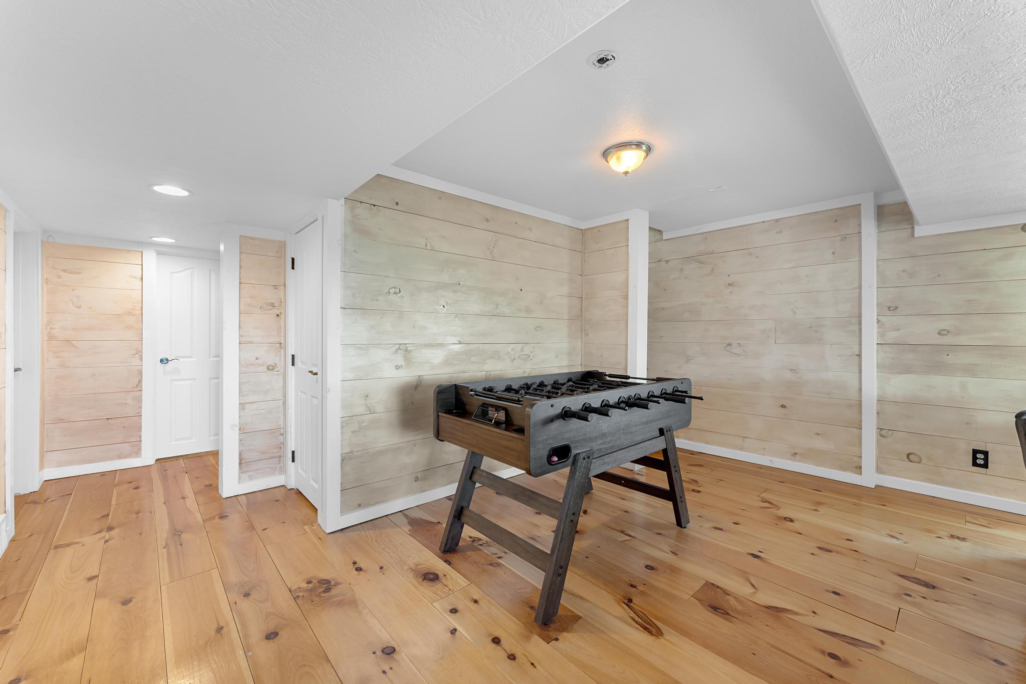 Spacious interior room featuring light wood-finish flooring, paneled walls, white trim, and a semi-flush mount ceiling light