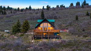 Log cabin exterior featuring a steep-pitched metal roof, two levels of outdoor decking, and a prominent gable with large windows