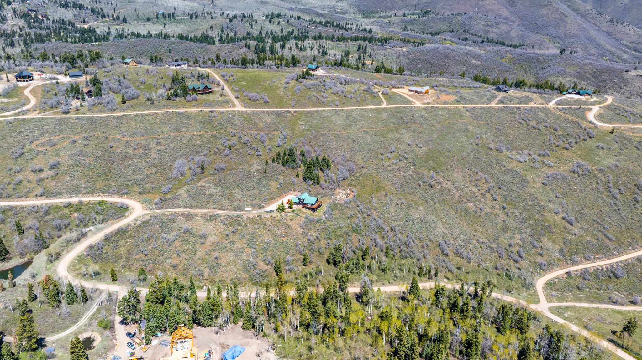 Expansive property featuring rolling hills, multiple residential structures, and winding unpaved roads