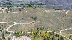 Expansive property featuring rolling hills, multiple residential structures, and winding unpaved roads
