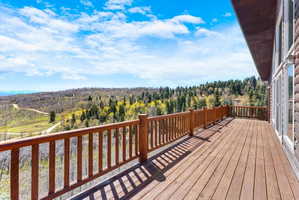 Expansive wood deck with a matching wood railing, offering sweeping mountain and forest scenery