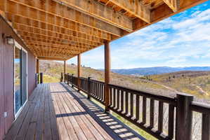 Expansive wood-plank deck featuring a natural wood ceiling, rustic wood railings, and a sliding glass door