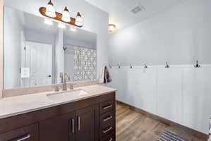 Bathroom featuring a dark wood-finish vanity with a light-toned countertop and an undermount sink