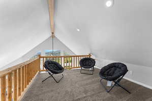 Loft area featuring a vaulted ceiling with exposed wood beam, recessed lighting, and a wood railing overlooking the surrounding scenery