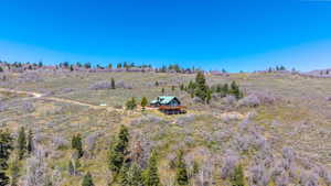 Spacious hillside property featuring a multi-level residence with a wood-finish exterior, a dark green roof, and a large wraparound deck