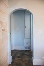 Hallway featuring arched walkways and baseboards