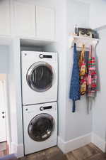 Main floor Laundry area with stacked washer / dryer and wood finished floors