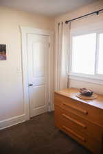Bedroom with dark colored carpet and baseboards