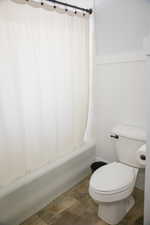 Full bathroom featuring wainscoting and shower / bathtub combination with curtain