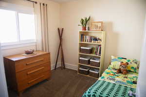 Bedroom with baseboards and dark carpet