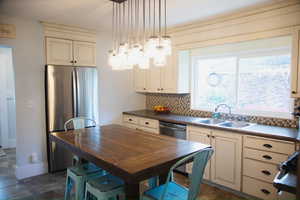 Kitchen with backsplash, dark countertops, stainless steel appliances, pendant lighting, and cream cabinets
