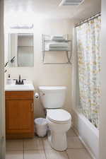 Full bathroom featuring vanity, light tile patterned flooring, a textured wall, and shower / bath combo