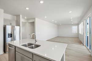 *DISCLAIMER*  Interior package and colors may vary. Kitchen featuring gray cabinetry, open floor plan, light wood-style flooring, recessed lighting, and a kitchen island with sink