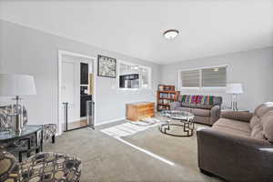 Living area featuring light colored carpet and baseboards