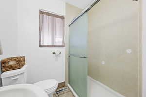 Bathroom with light tile patterned flooring and a shower stall