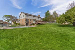 Rear view of house featuring basketball hoop, a deck, and stone siding