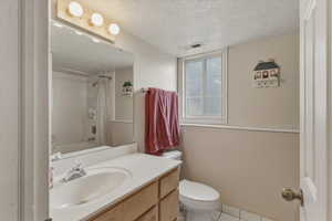 Full bath with a textured ceiling, vanity, shower / bath combination with curtain, and light tile patterned flooring