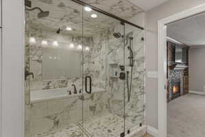 Bathroom featuring a bath, carpet flooring, a marble finish shower, and a stone fireplace