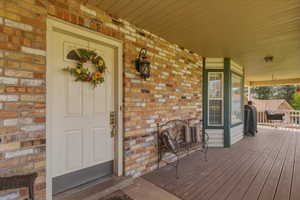 View of exterior entry with covered porch and brick siding