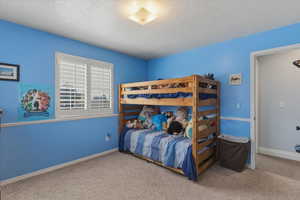 Bedroom with a textured ceiling and light carpet